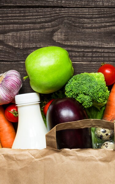 Full paper bag of different health food on rustic wooden background. Top view. Flat lay