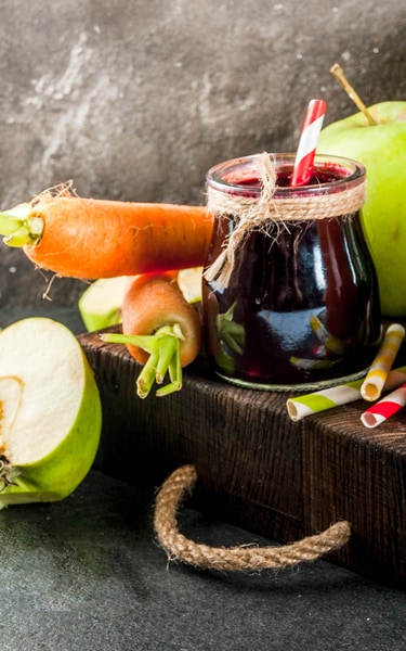 Vegan diet food. Detox drinks. Freshly squeezed juices and smoothies from vegetables: beets, carrots, spinach, cucumber, apple. On dark stone background, wooden tray, ingredients. Copy space