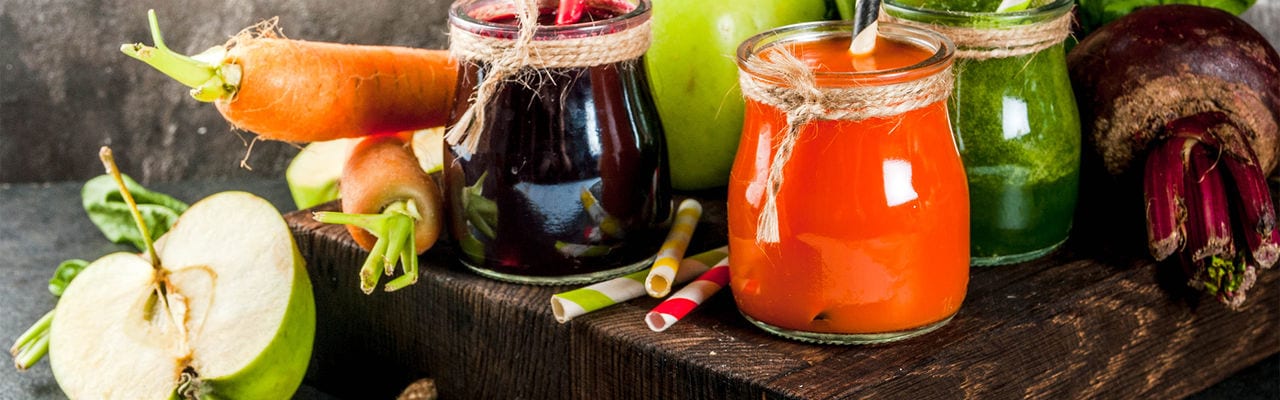 Vegan diet food. Detox drinks. Freshly squeezed juices and smoothies from vegetables: beets, carrots, spinach, cucumber, apple. On dark stone background, wooden tray, ingredients. Copy space